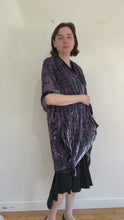 Load and play video in Gallery viewer, women in video modeling devoré or burnout velvet kimono jacket showing all sides. Duster length jacket  over black dress. The duster style jacket is black sheer chiffon background with an all over pattern of willow branches with purple accents.