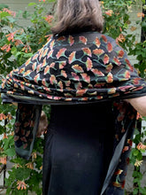 Load image into Gallery viewer, orange bak of  flowers on black burnout velvet scarf worn by women  with honeysuckle flowers in background
