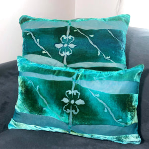 Two aqua blue rectangular hand painted burnout velvet Pillows with fleur de lis center on gray couch